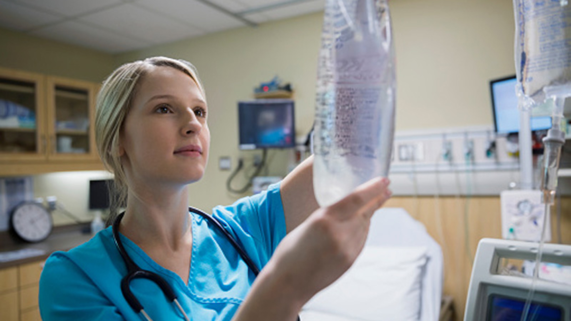 Nurse hanging IV drip bag in hospital room